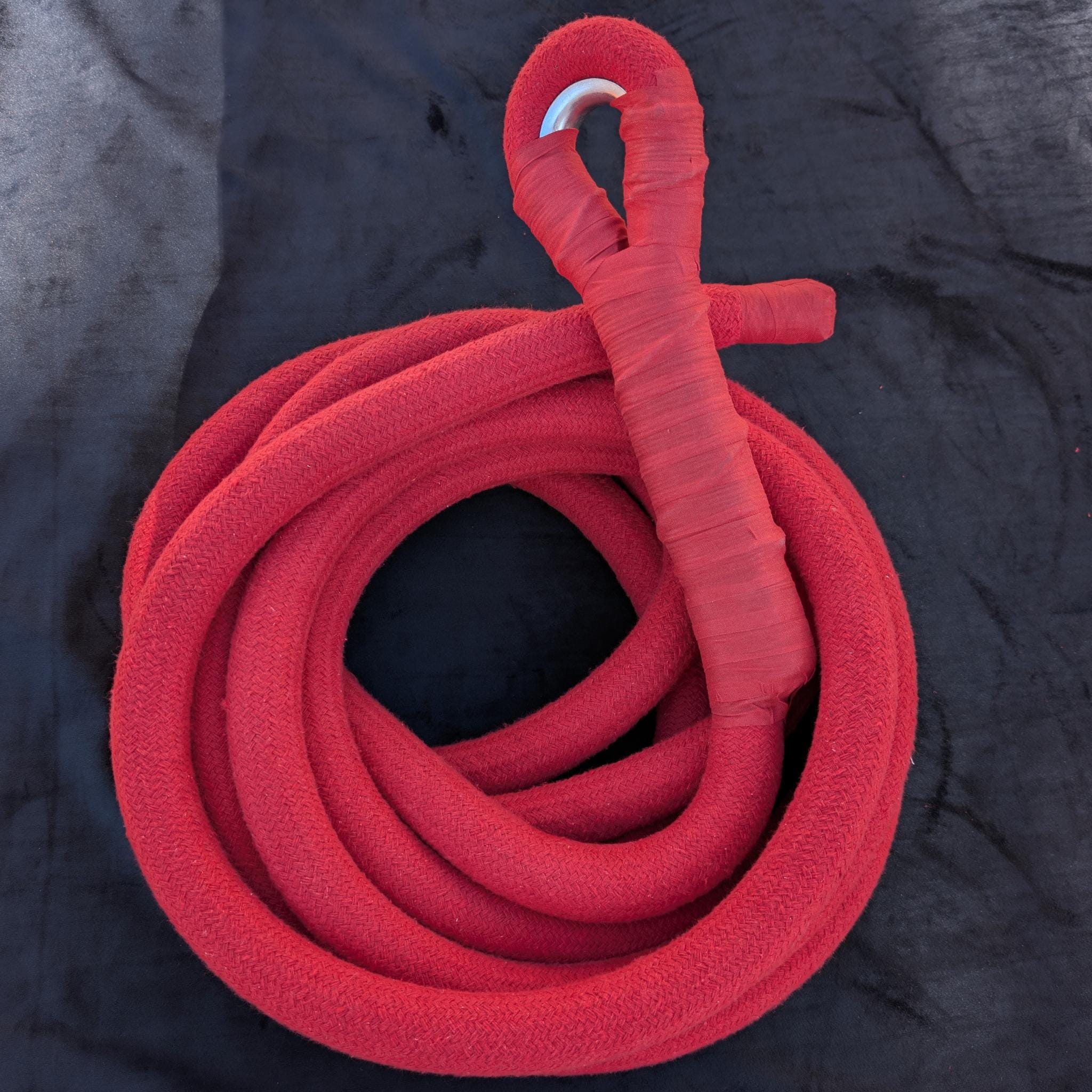 Red corde lisse aerial rope by Aerial Obsessed, coiled, with the spliced eye and thimble at the top